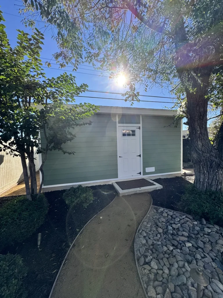 Custom shed with Hardie lap siding and white trim at the end of a landscaped garden path